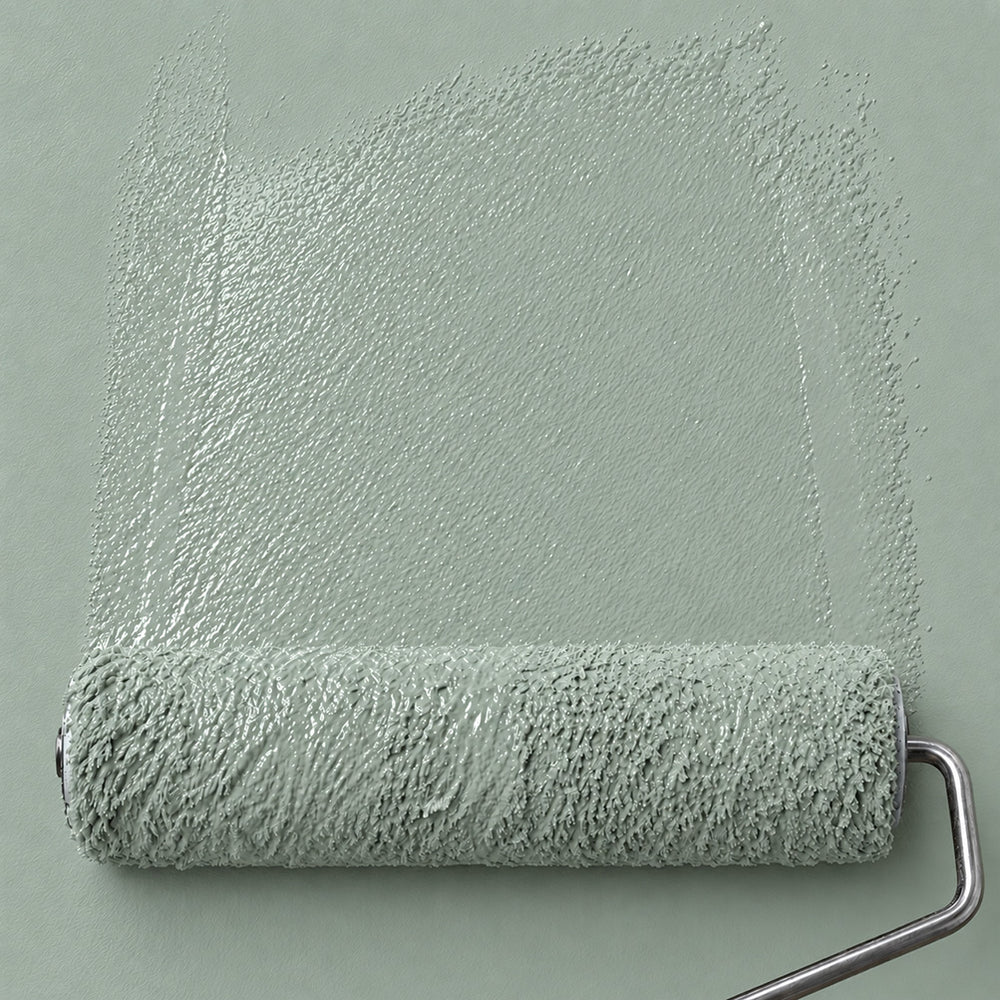 Paint roller spreading Eucalyptus Veil soft sage green paint across a matching wall.