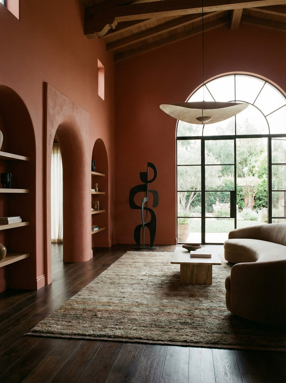 Modern living room with pink walls, wooden floor, and large window.
