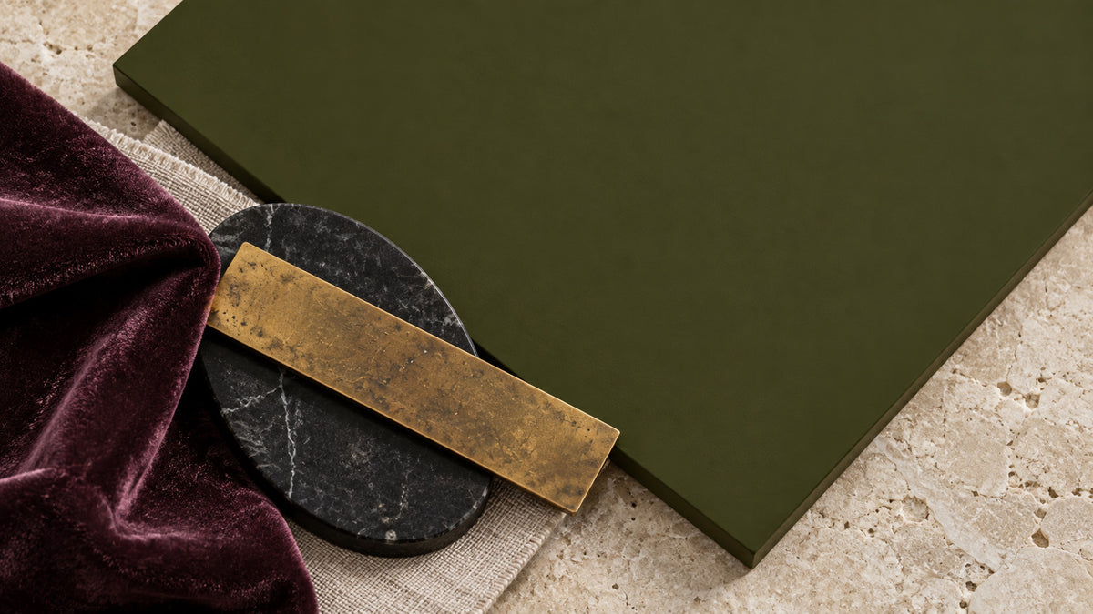 Garden Armory dark olive green paint paired with plum velvet, black stone, aged brass, and pale limestone.