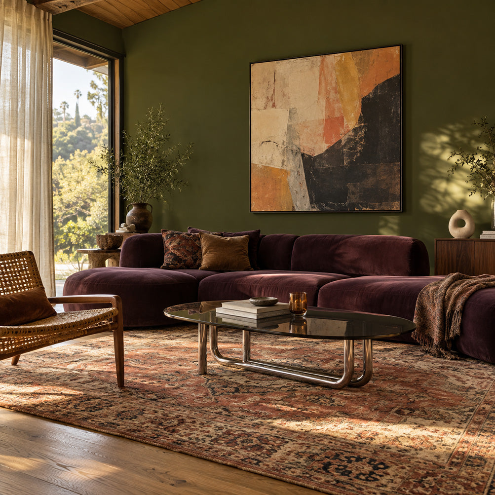 Garden Armory dark olive green walls with a plum velvet sofa, smoked glass coffee table, and vintage rug.