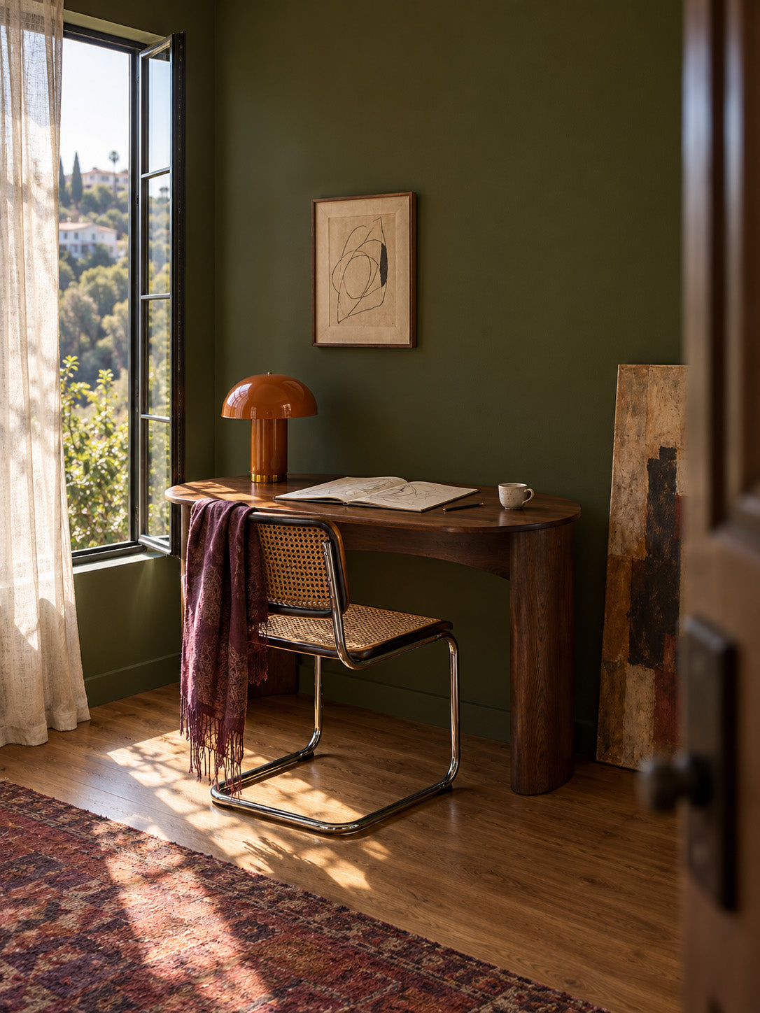 Garden Armory dark olive green paint in a vintage office nook with a walnut desk, cane chair, and orange lamp.