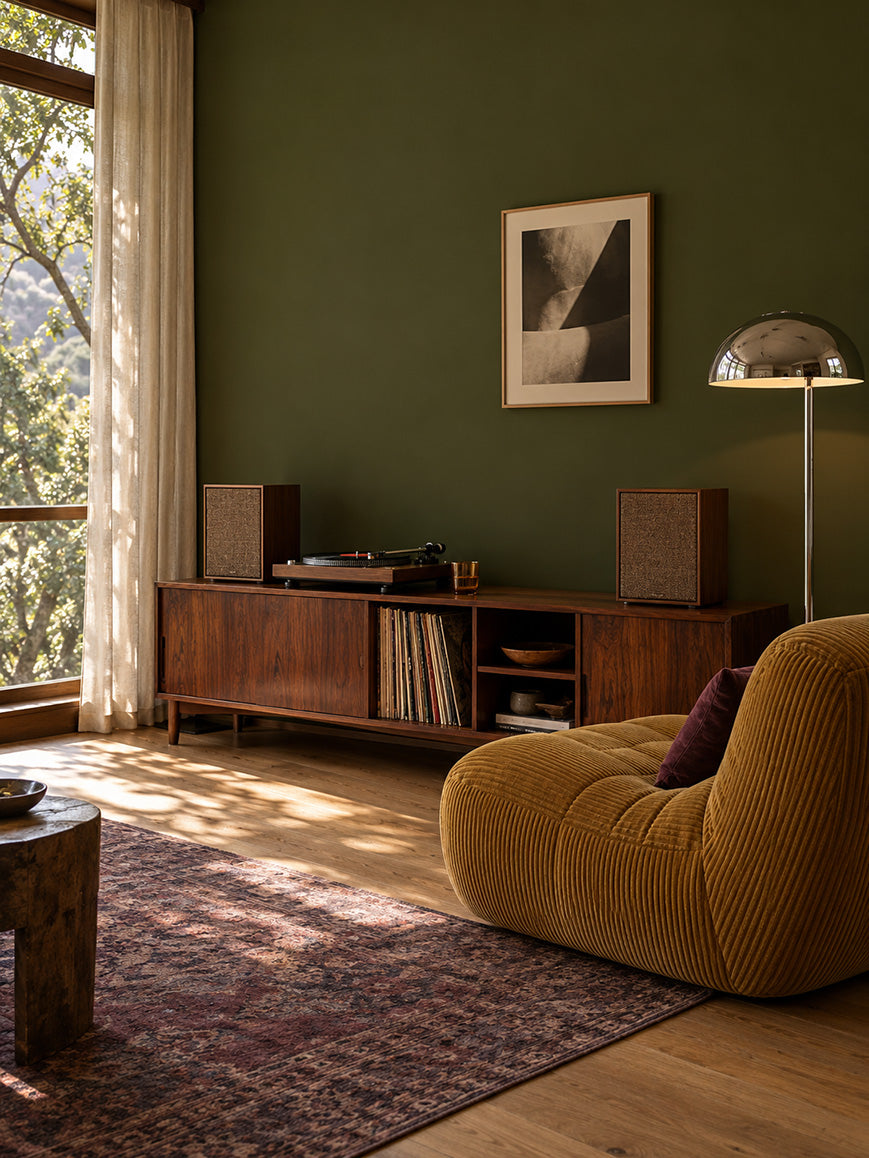 Garden Armory dark olive green walls with an ochre lounge chair, vintage record console, and chrome floor lamp.