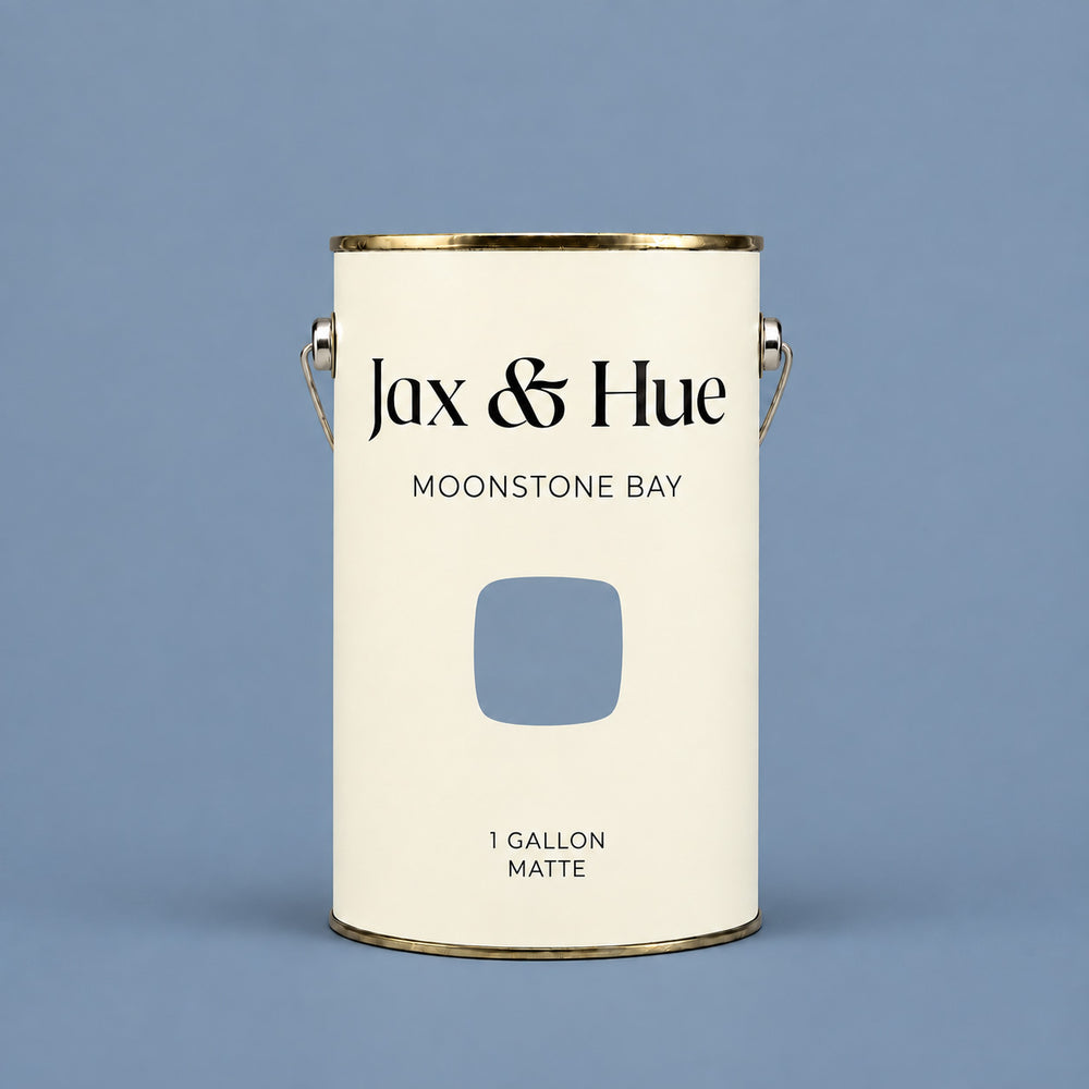 Jax & Hue Moonstone Bay muted blue-grey matte paint gallon on a matching blue background.