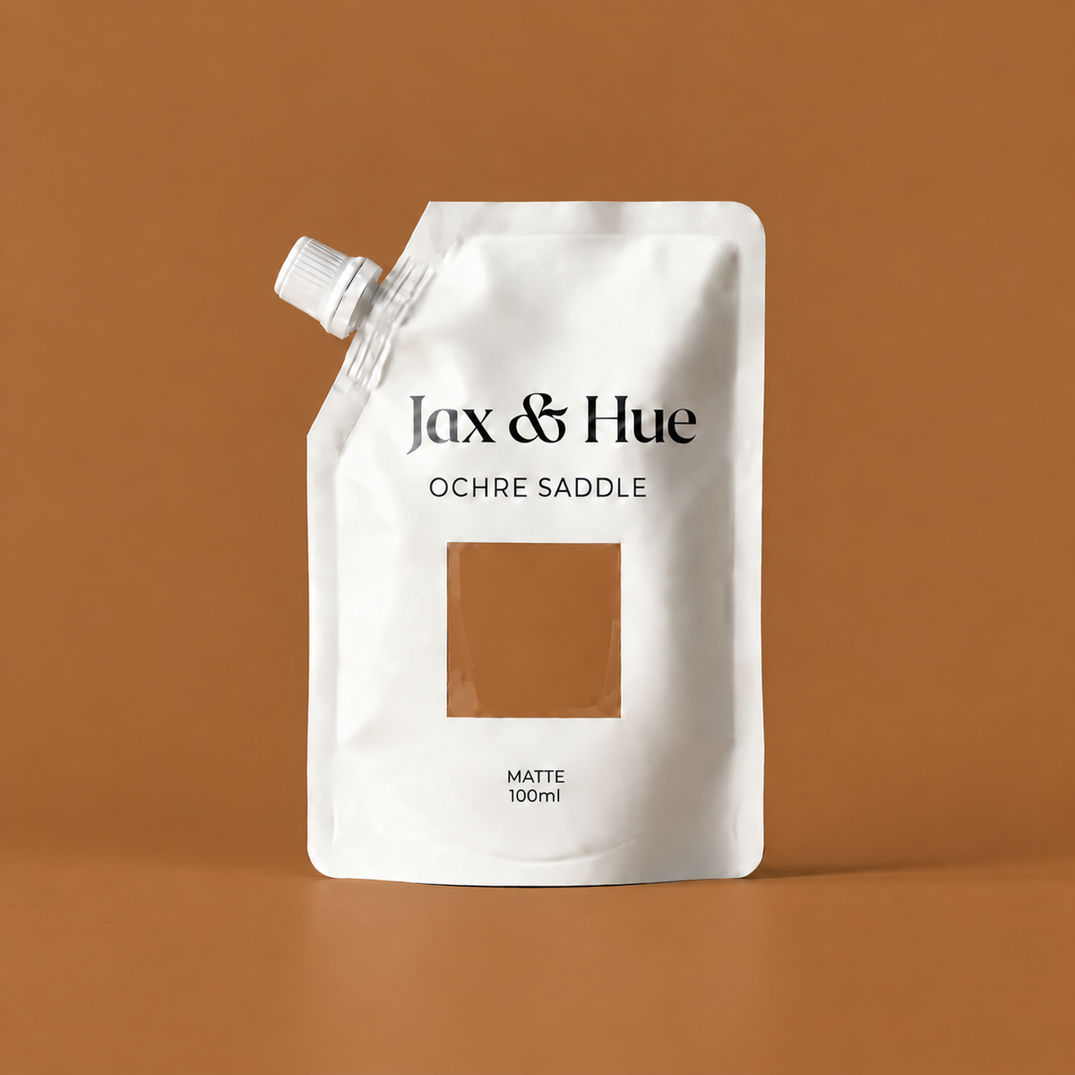 Jax & Hue Ochre Saddle Color Tester pouch showing a warm, saturated ochre brown paint color against a copper-brown backdrop.