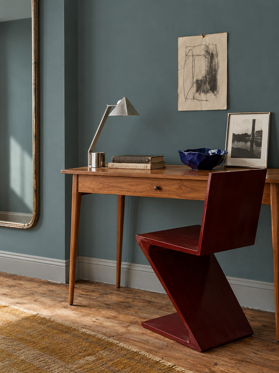Salt Fjord smoky blue-grey walls behind an elm desk, burgundy sculptural chair, and metal task lamp.