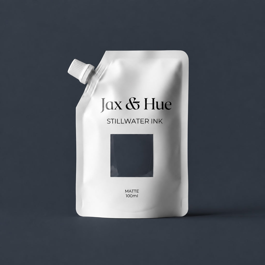 Stillwater Ink 100ml Color Tester pouch by Jax & Hue, a dark blue-gray paint sample, on a matching inky background.