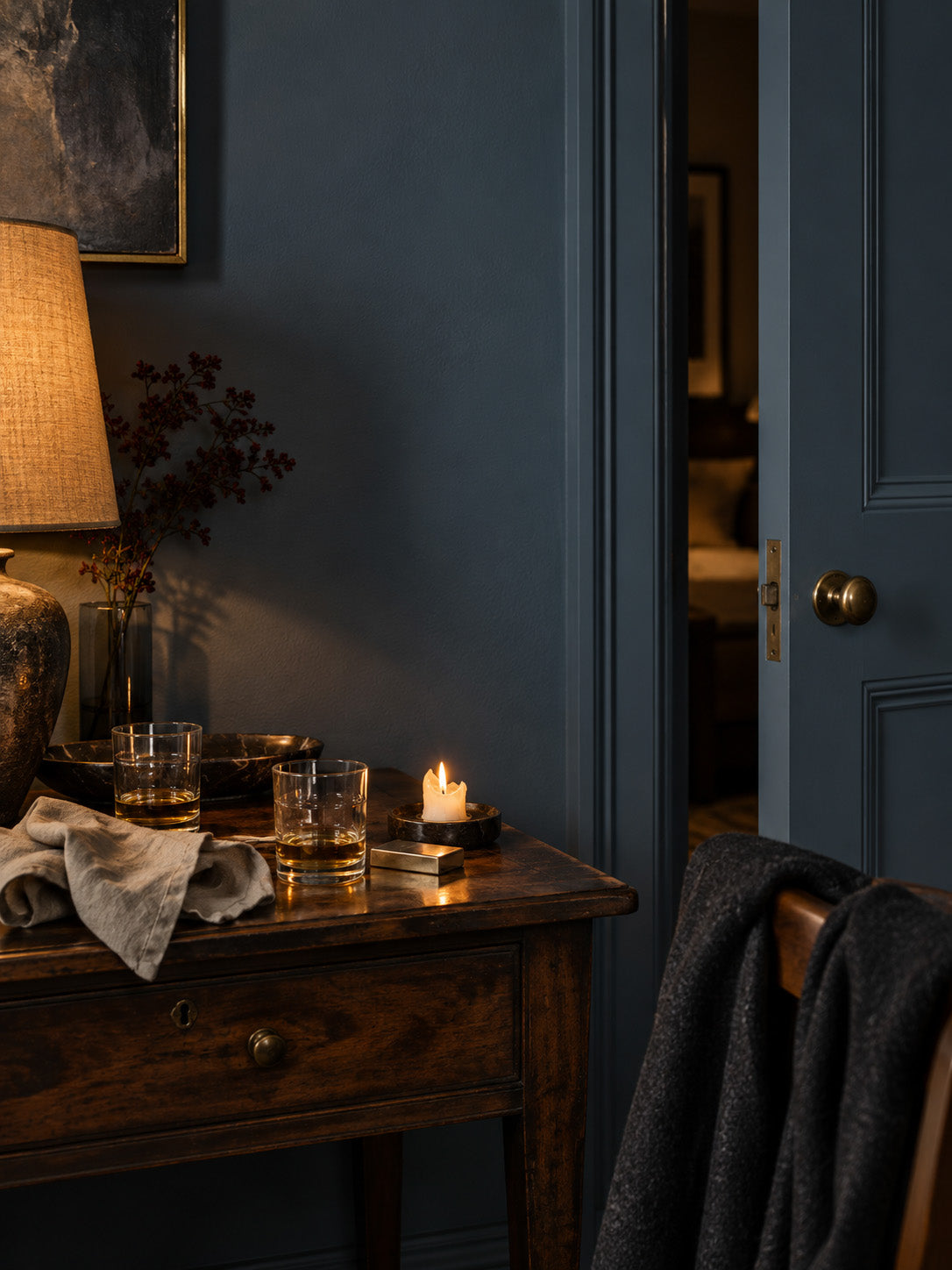 Tempest Slate slate blue-gray entryway with a partially open door, warm lamplight, and dark wood furniture