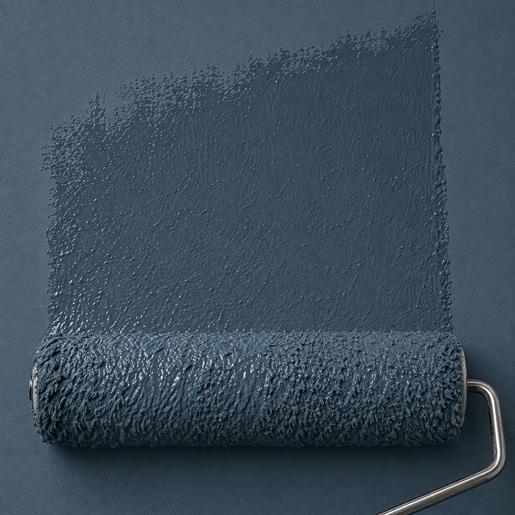 A paint roller covered in dark slate blue paint, shown against a matching dark slate blue textured background with a painted stroke extending upward behind it.