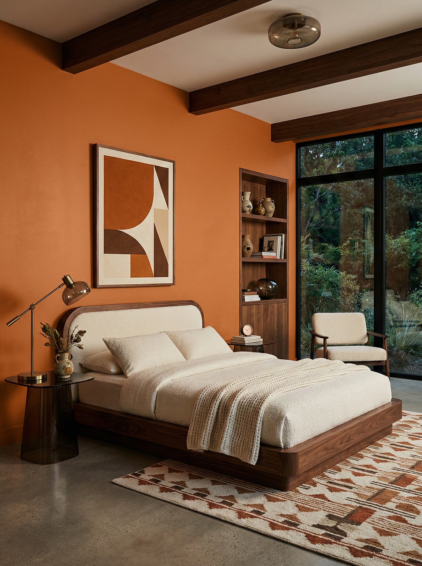 Modern bedroom with terracotta orange paint, wooden bed frame, and abstract art.